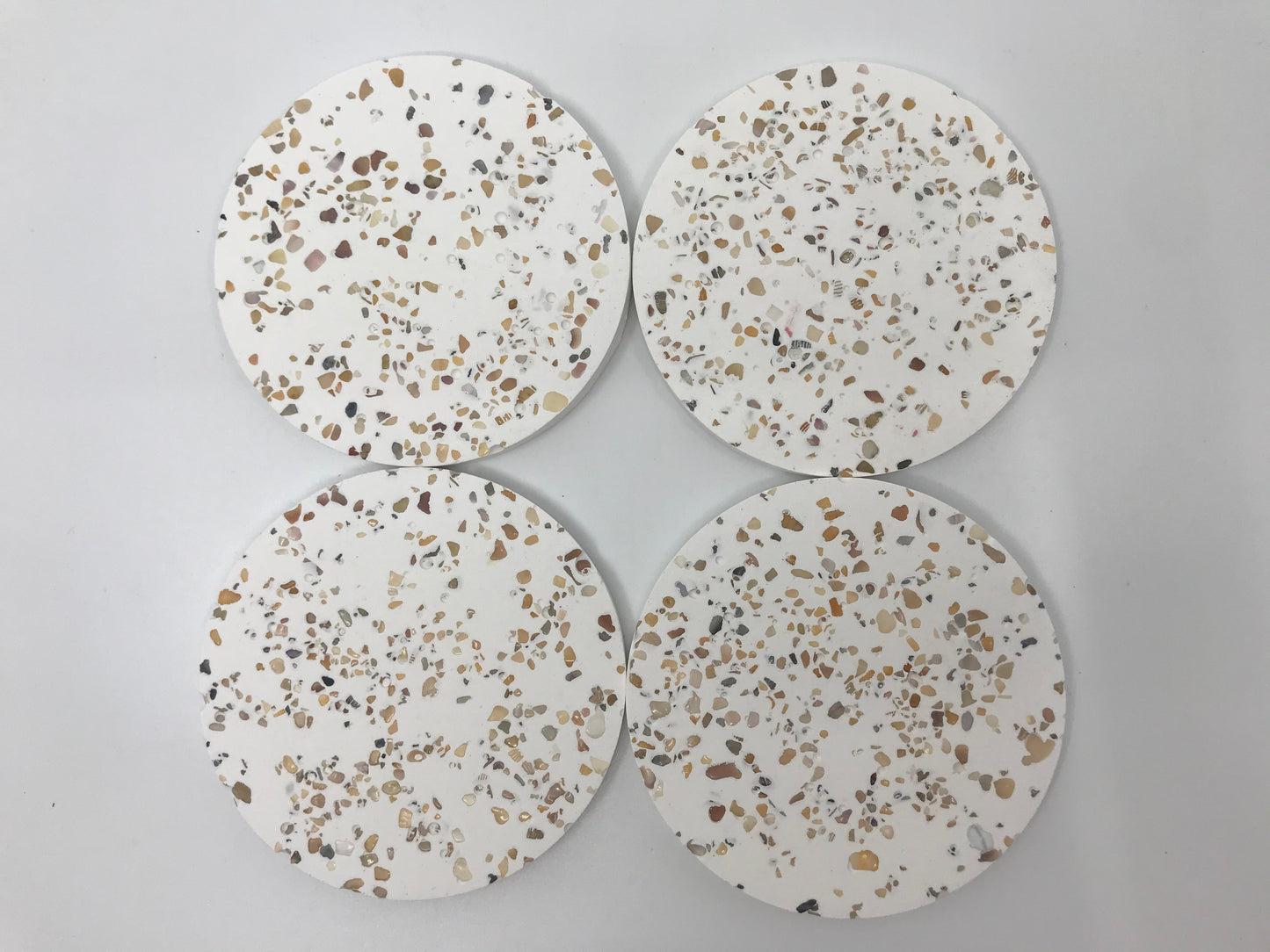 Four round terrazzo coasters on a light gray background