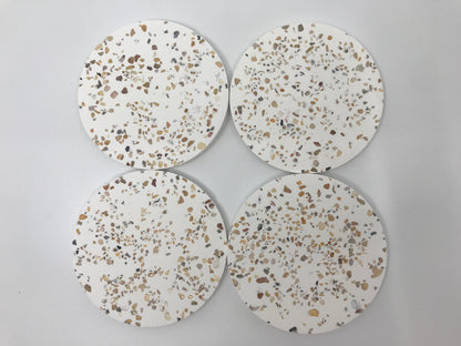 Four round terrazzo coasters on a light gray background